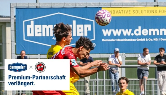 Header duel at an FC Memmingen match in front of the DEMMELER banner, with the DEMMELER and FC Memmingen logos and the words "Premium-Partnerschaft verlängert." in the bottom left corner